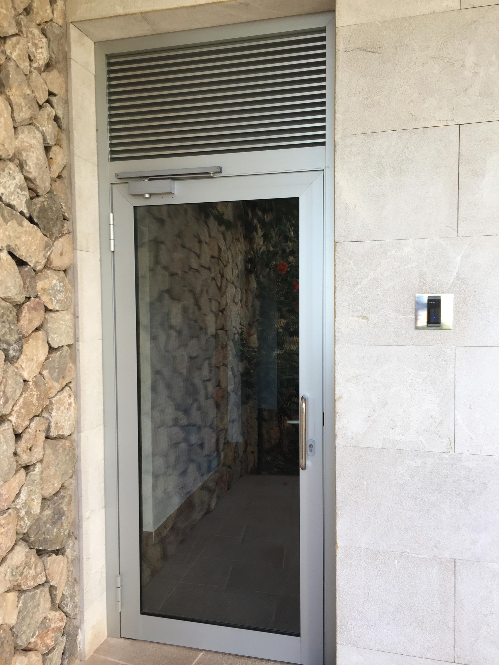 Una puerta de cristal con una pared de piedra detrás.