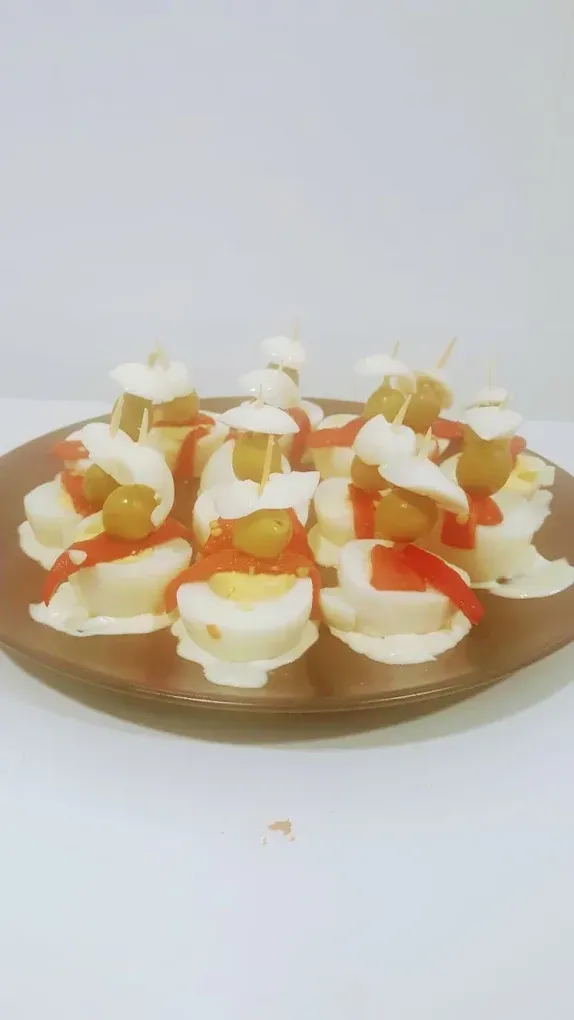 Bandeja de vasitos de postre pequeños cubiertos con crema blanca y trozos de fruta naranja