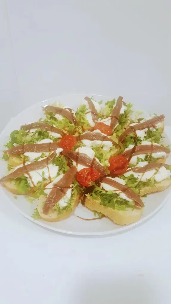 Plato de galletas saladas cubiertas con lechuga, tomate y salsa sobre un fondo blanco