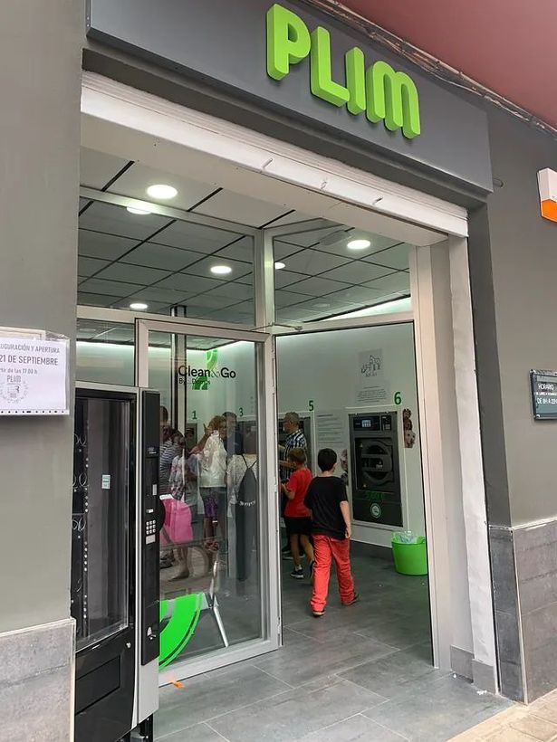 Un grupo de personas se encuentra afuera de una tienda de ciruelas.