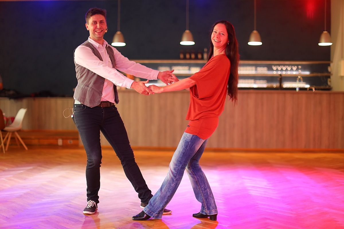 Zwei Personen tanzen West Coast Swing auf einer beleuchteten Tanzfläche