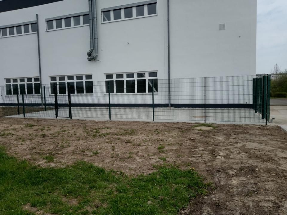 Ronny Mätzold Maurer- und Betonarbeiten – frisch betonierte Fläche an einem Gebäude hinter einem grünen Zaun