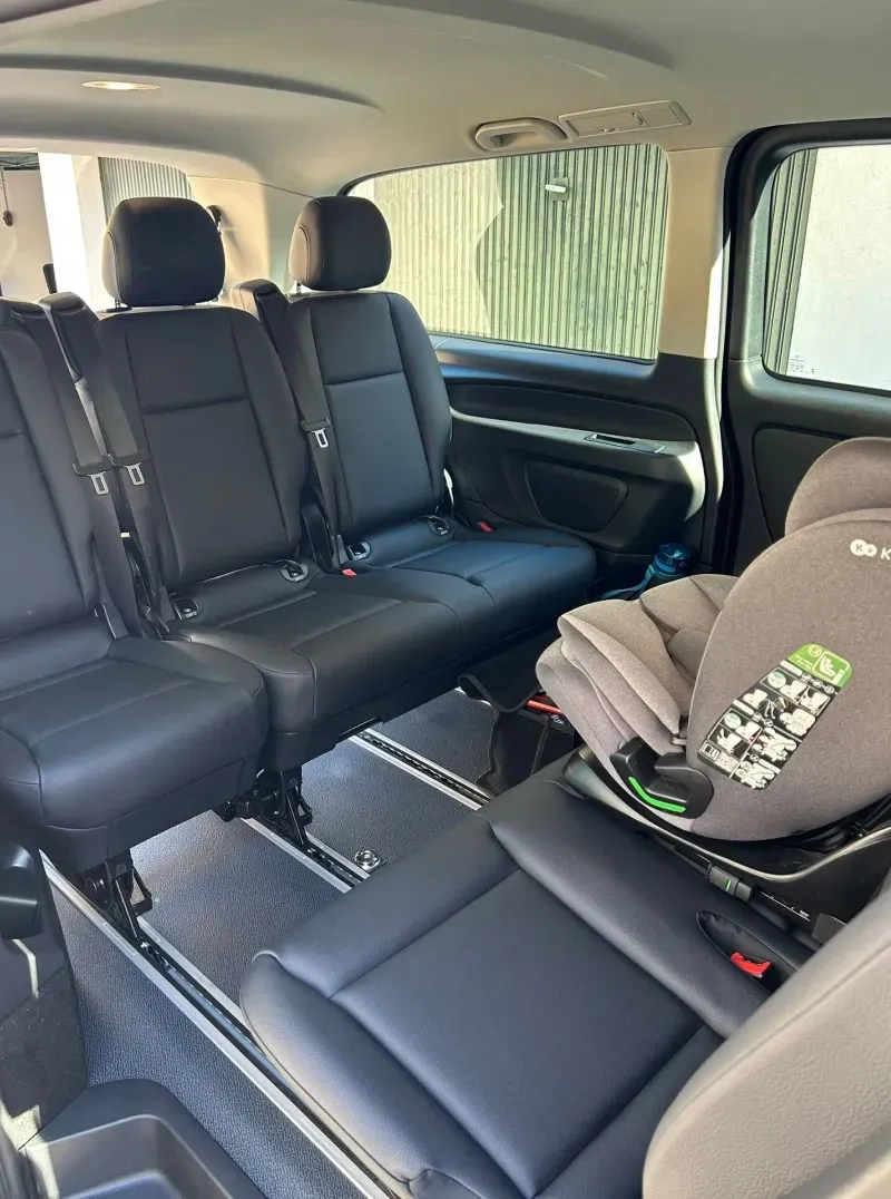 Une personne en fauteuil roulant monte dans une camionnette noire par la rampe d'accès arrière, à l'extérieur près du parking.