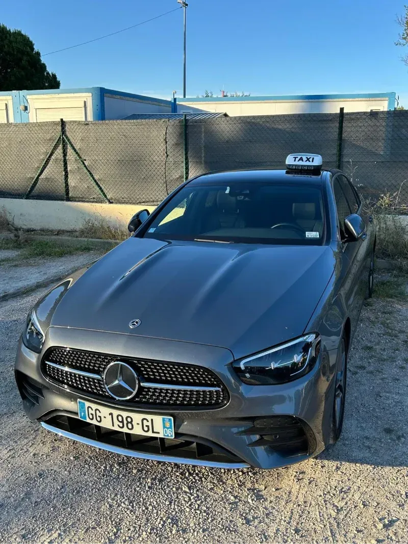 Une berline Mercedes gris foncé est garée sur une route sinueuse sous un ciel nuageux.
