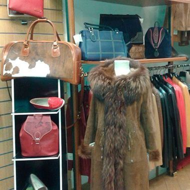 Un escaparate con bolsos, un abrigo de piel y percheros con ropa.
