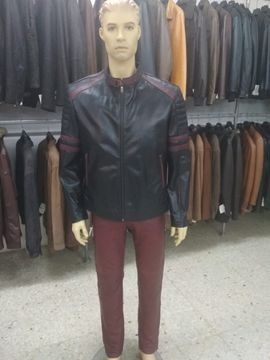 Maniquí con una chaqueta de cuero negra con rayas rojas, combinada con pantalones burdeos, en una tienda de chaquetas de cuero.
