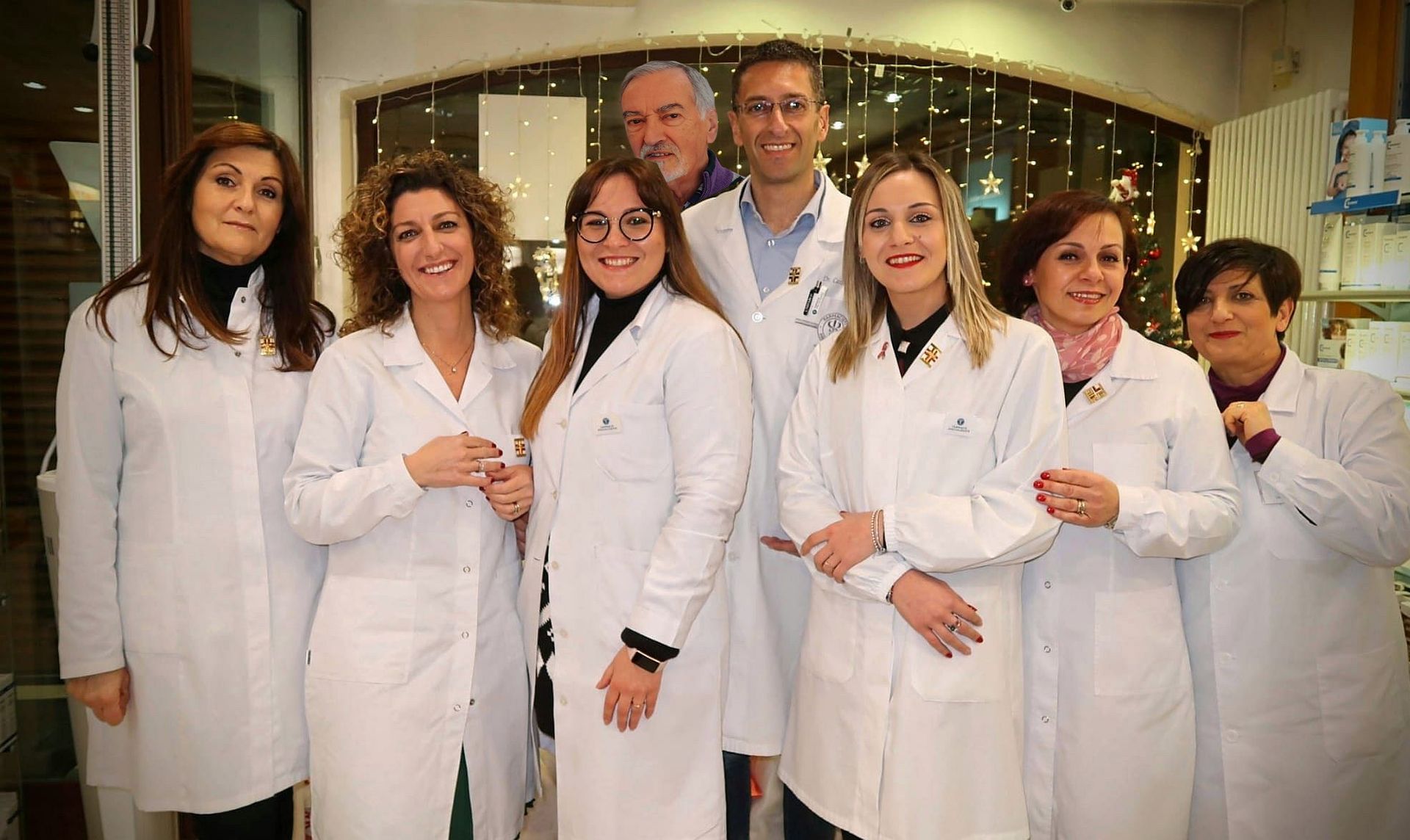 Donna in camice bianco in una farmacia, mentre controlla l'inventario dei farmaci sugli scaffali.