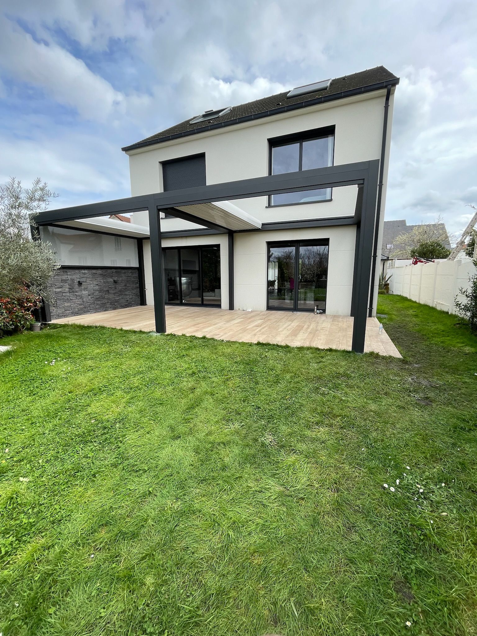 Maison moderne à deux étages avec pergola noire et portes coulissantes en verre