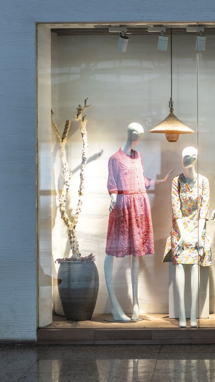 Vitrine d'un magasin présentant deux mannequins en robe. L'un est debout, l'autre assis.