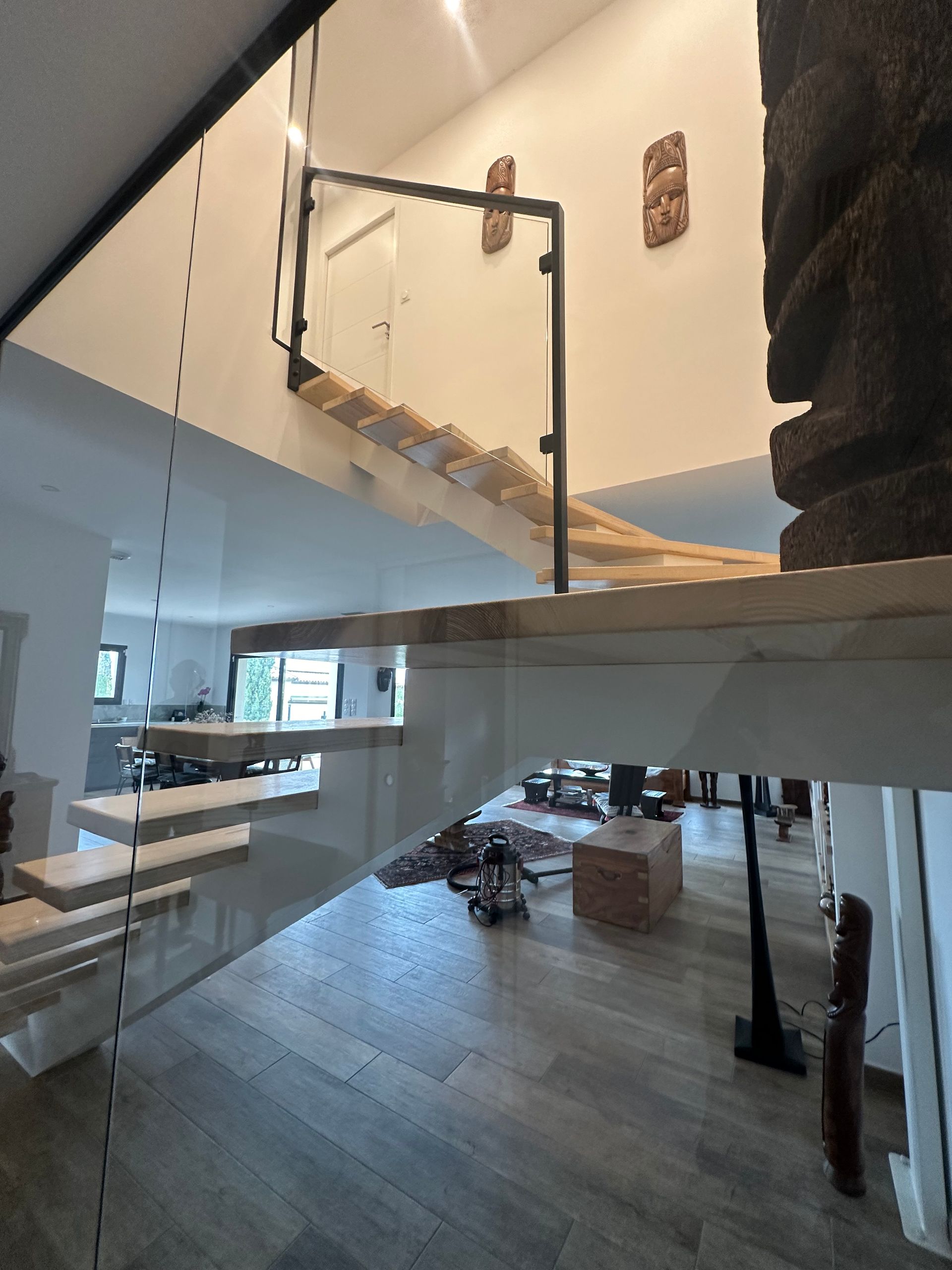 Intérieur moderne avec escalier à balustrade en verre et parquet.