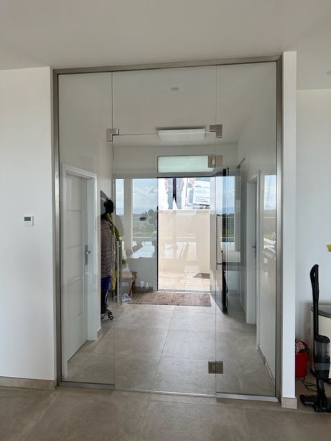 Porte vitrée et cadre donnant sur l'intérieur ; une personne dans le couloir.