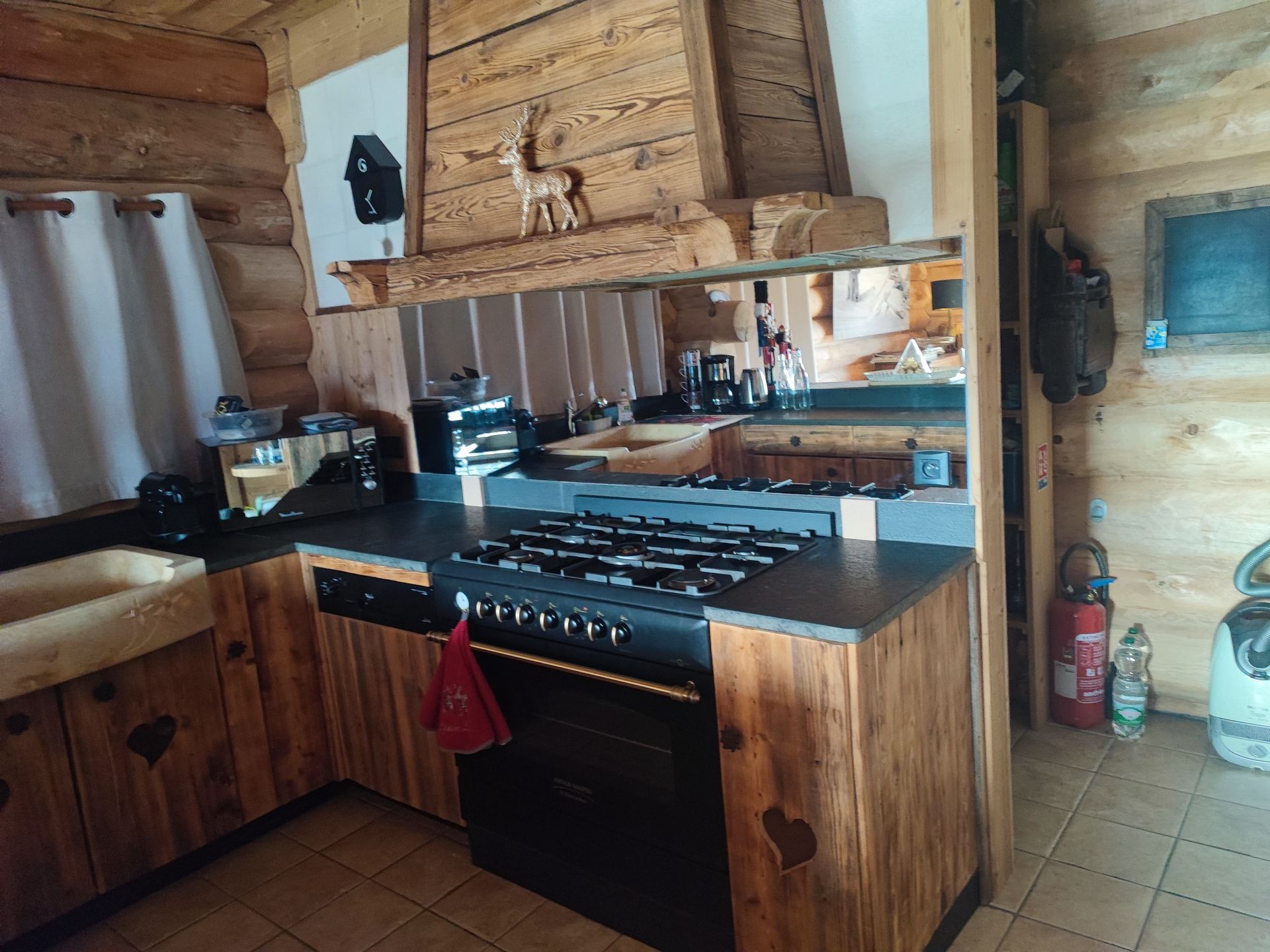 Cuisine rustique en bois de cabane avec plaque de cuisson, placards et hotte aspirante.
