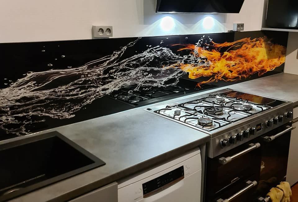 Cuisine avec plan de travail noir, plaque de cuisson et crédence effet eau/feu.