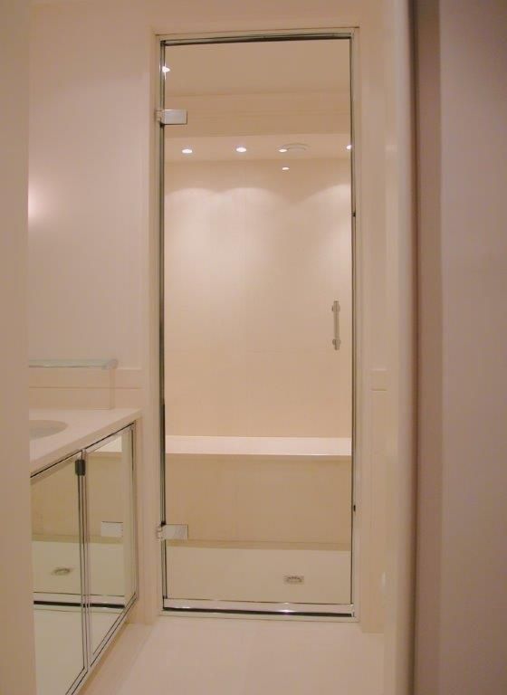 Porte de douche en verre dans une salle de bains blanche.