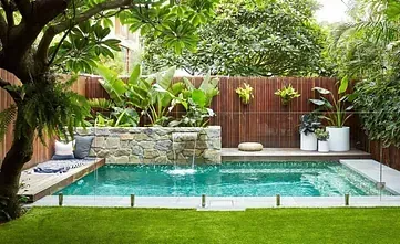Una pequeña piscina con cascada en el patio trasero.