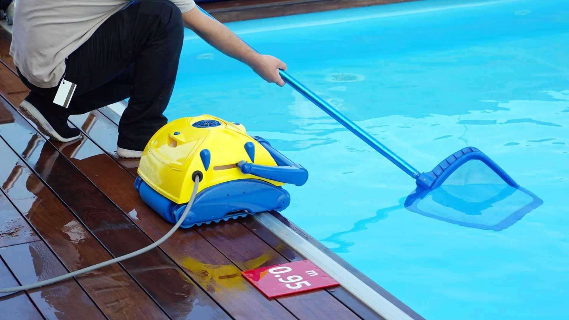 Una persona está limpiando una piscina con una aspiradora robótica.