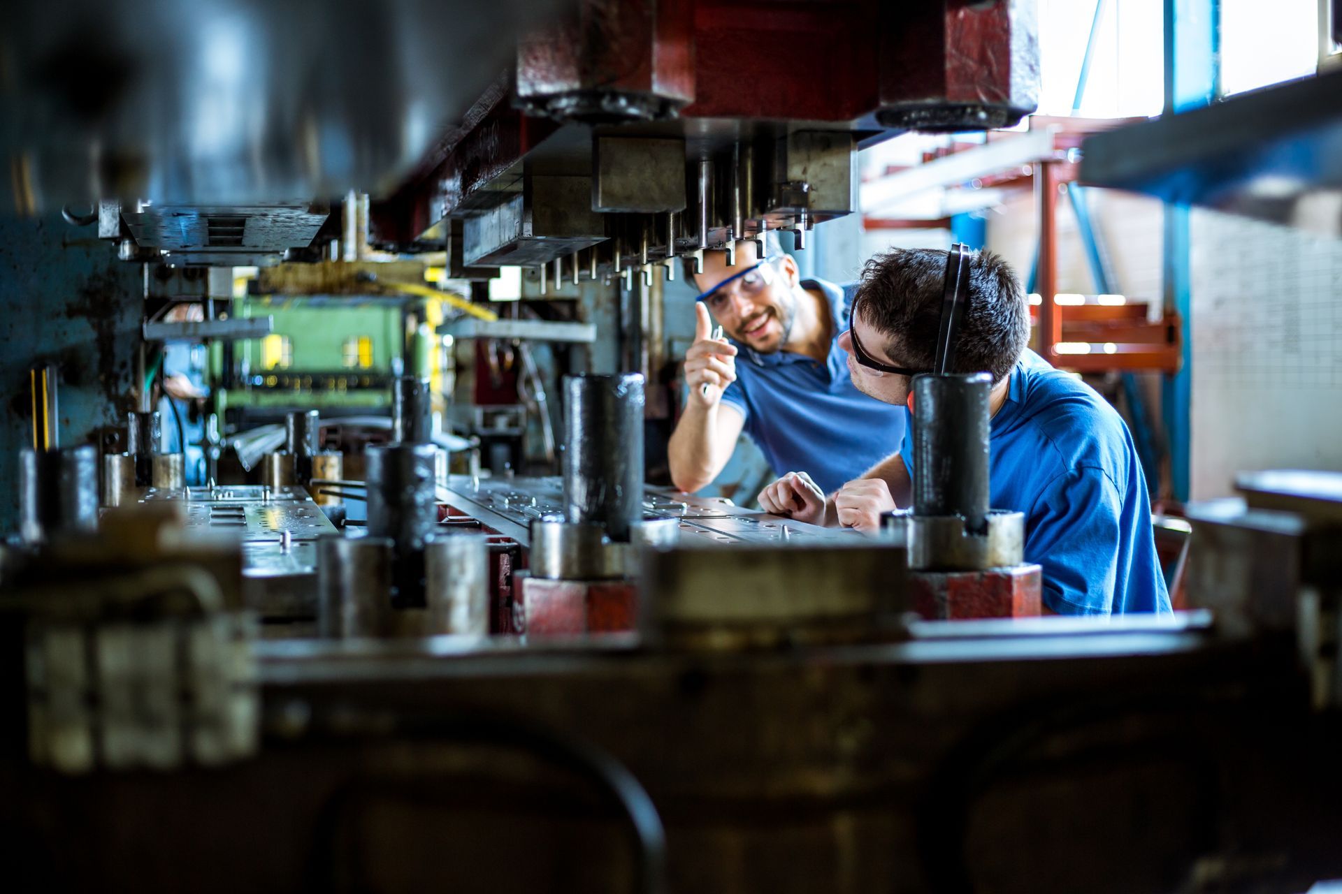 Deux hommes portant des lunettes de protection devant une machine de découpe