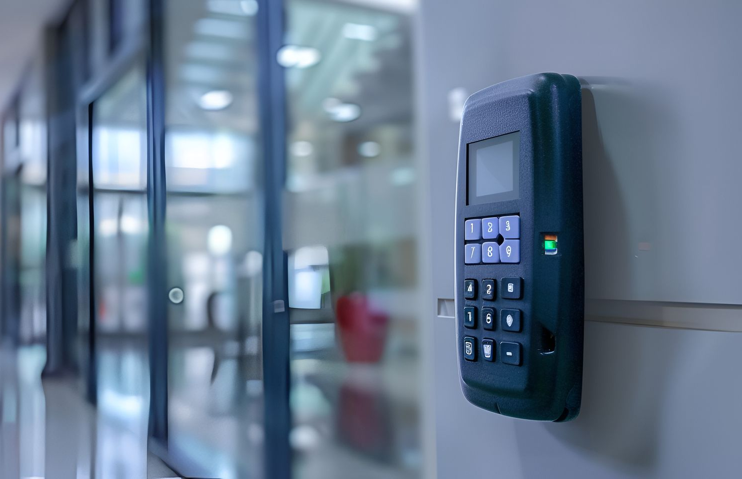 Dispositif de contrôle d'accès par clavier mural dans un couloir de bureau ; portes vitrées floues en arrière-plan.