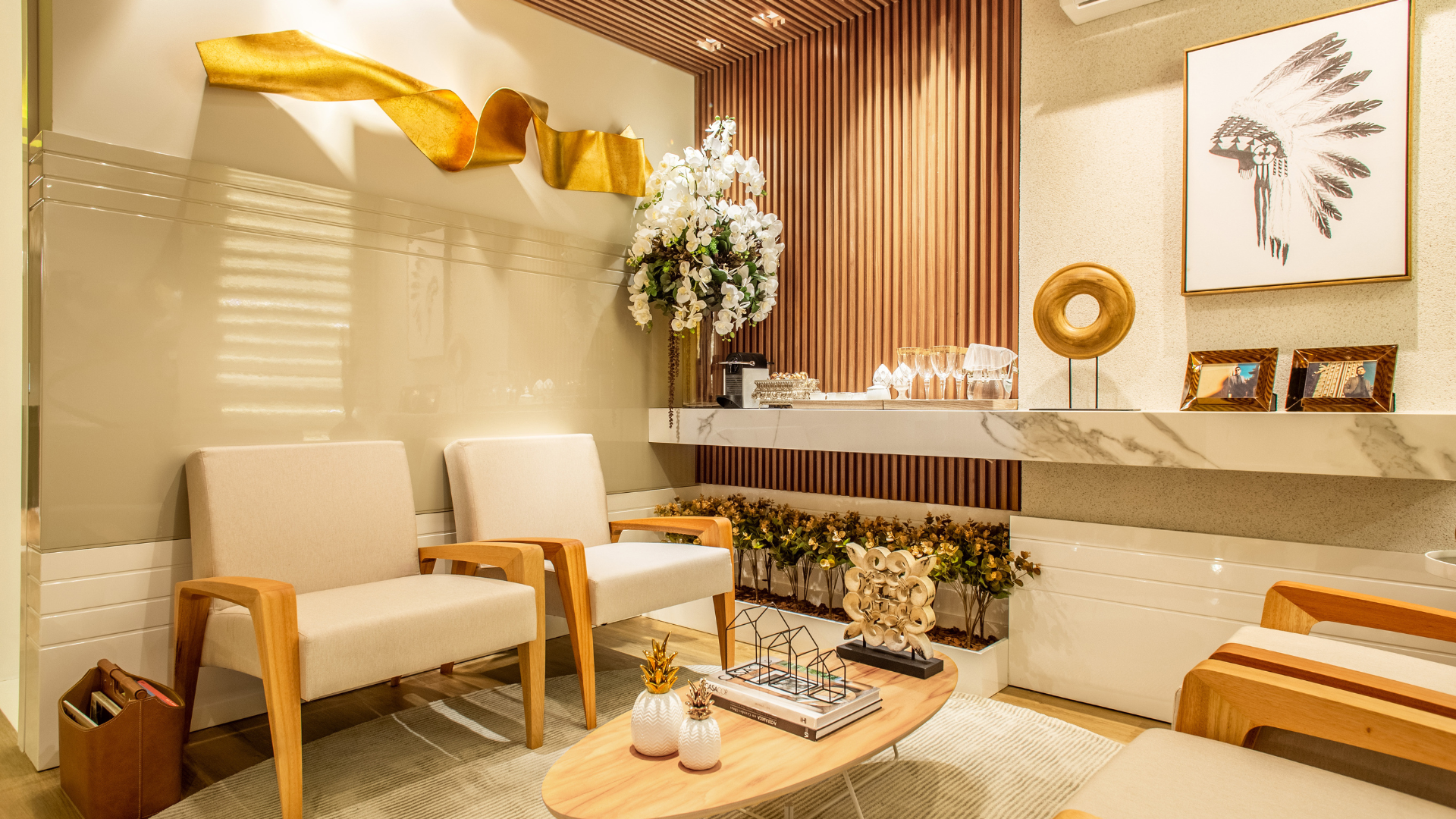 Salle d'attente avec deux chaises beiges, des œuvres d'art, des fleurs et un bureau en marbre.