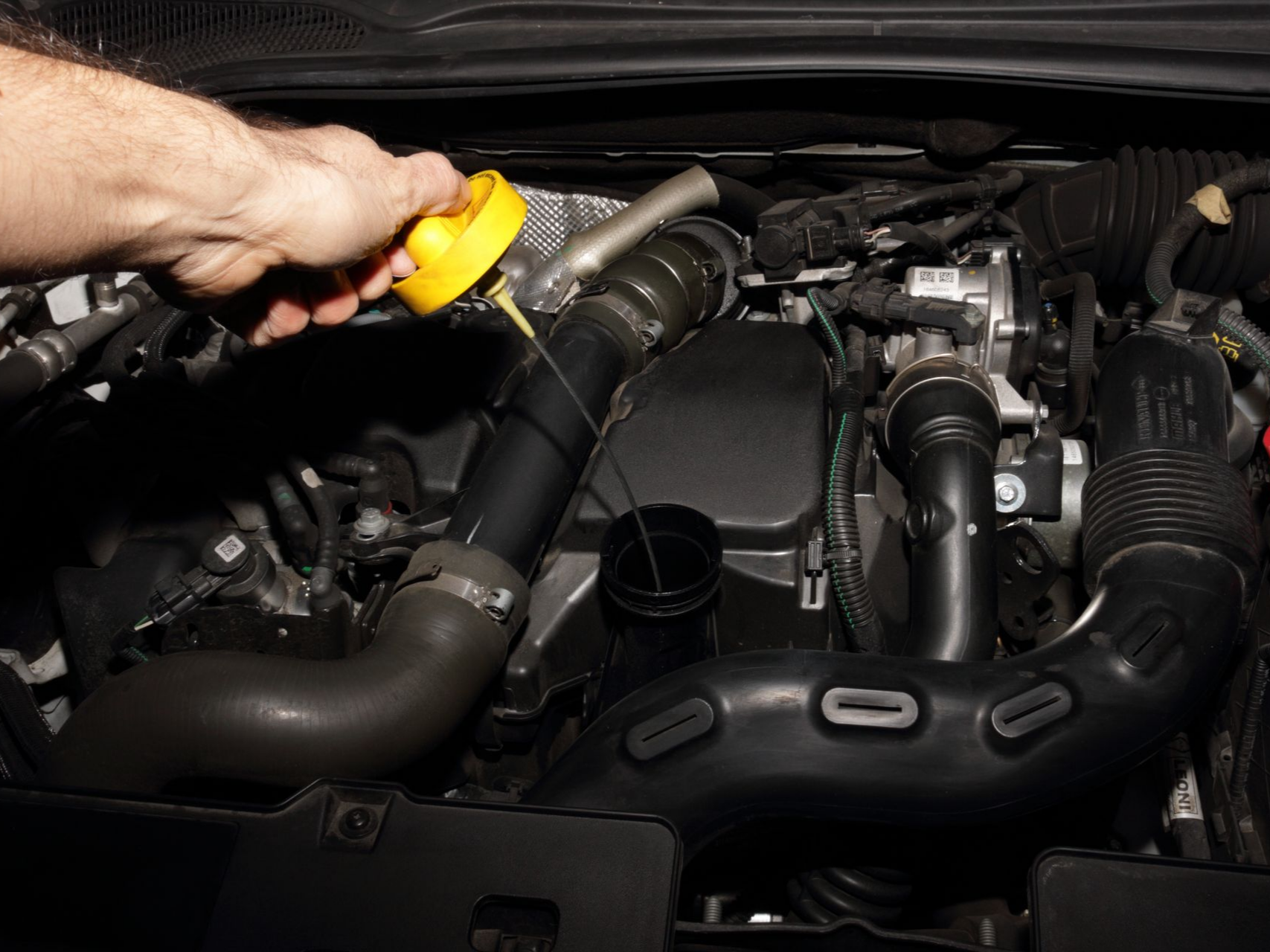 Une personne tient un bouchon d'huile jaune.