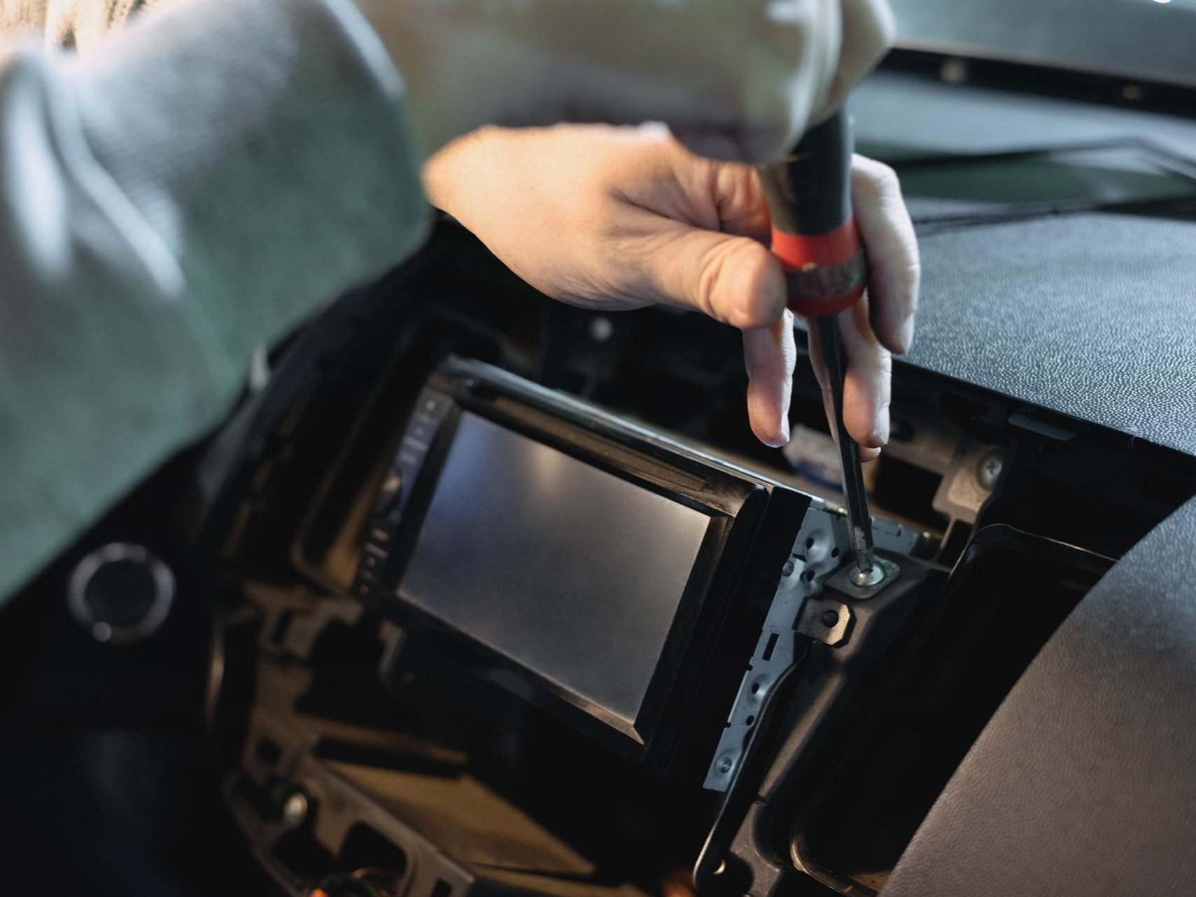 Des mains utilisant un tournevis pour retirer ou installer un autoradio.