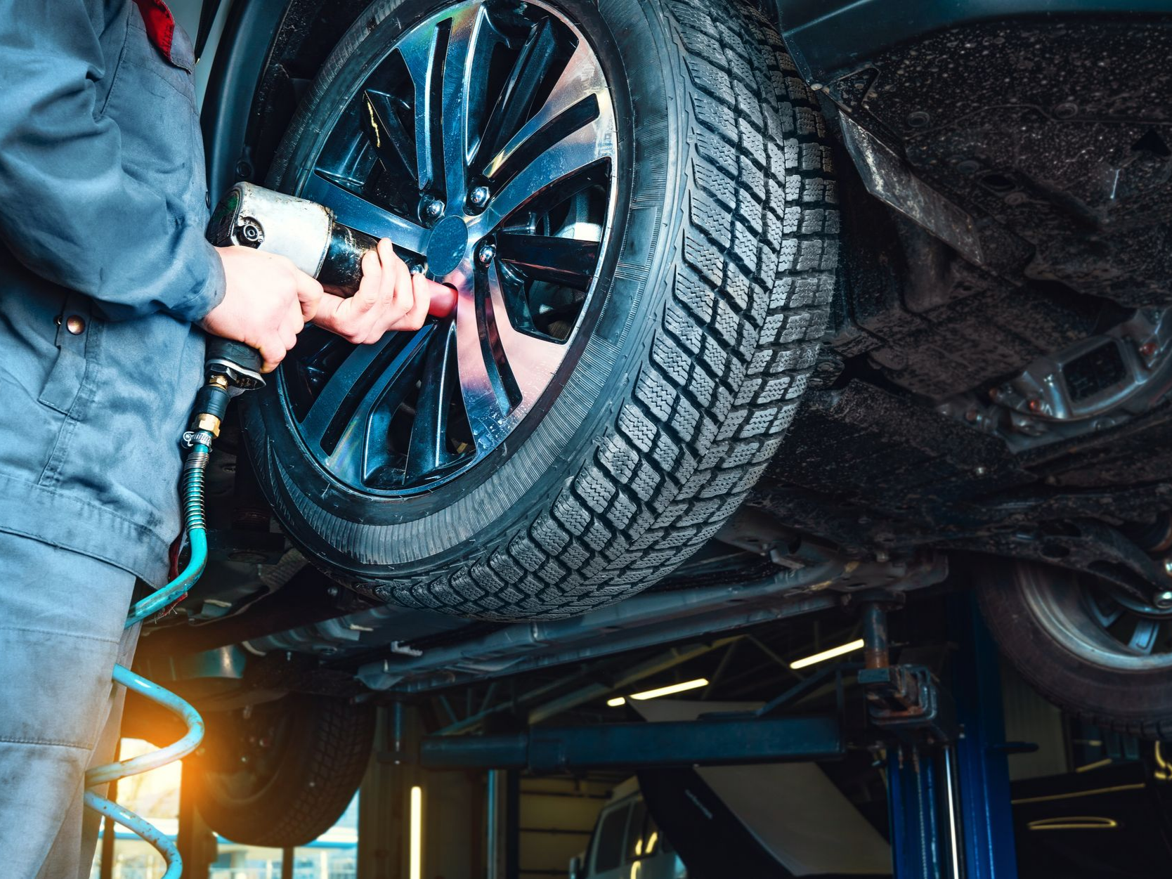 Un mécanicien utilise une clé à chocs pour serrer les écrous de roue d'une voiture.