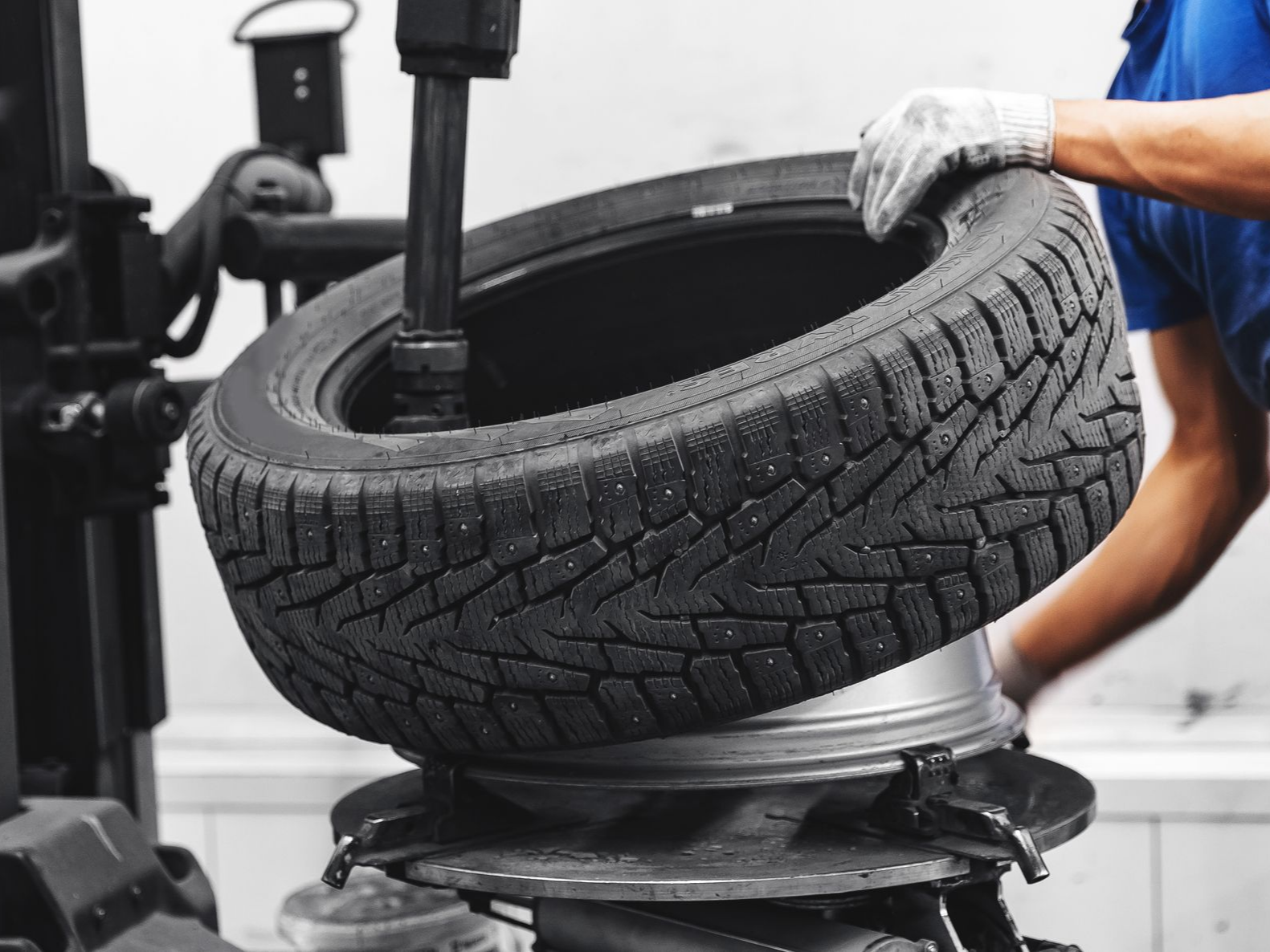 Un technicien utilise une machine industrielle pour monter un pneu sur une jante.