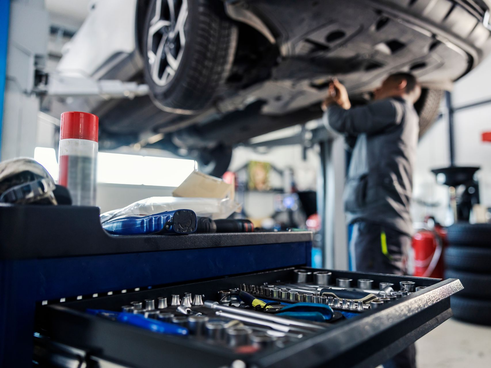 Un mécanicien travaille sur le châssis d'une voiture soulevée dans un garage.