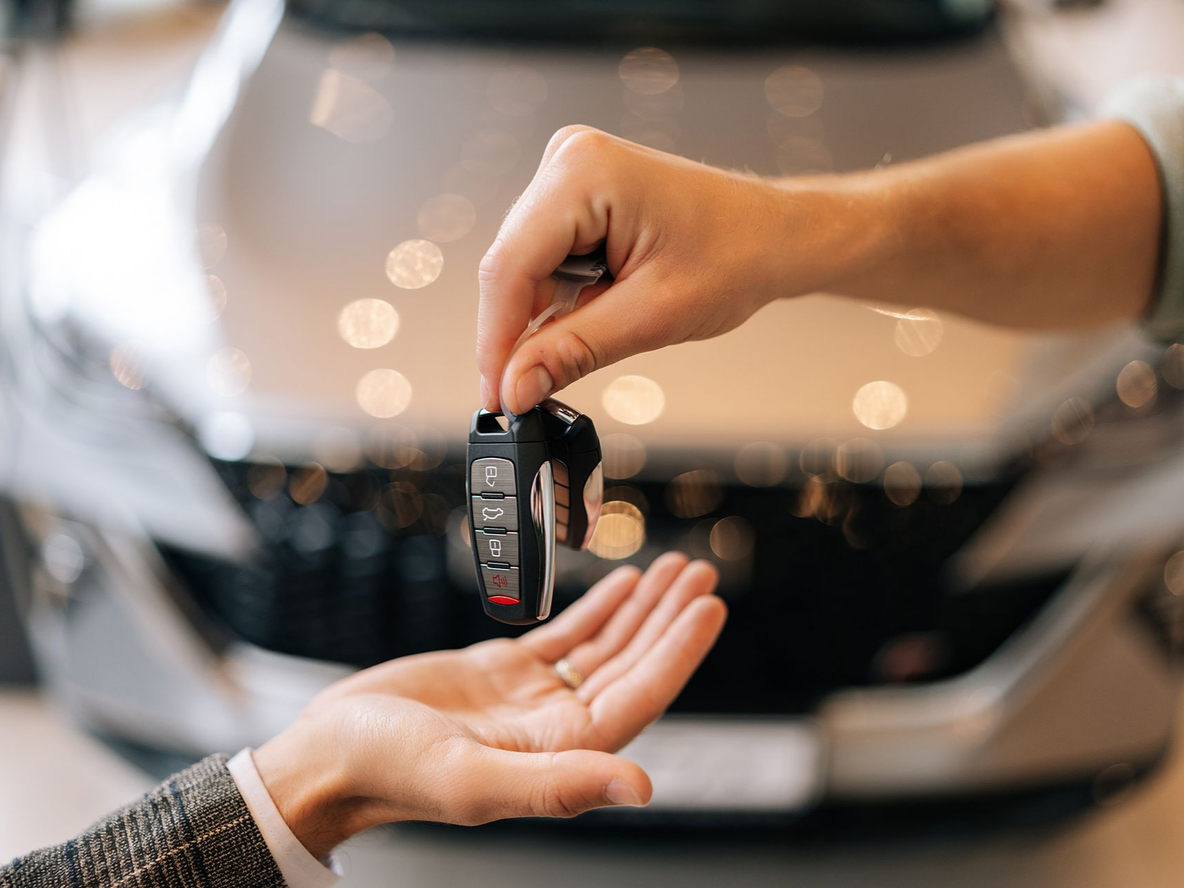 Une main remet des clés de voiture à une autre personne.