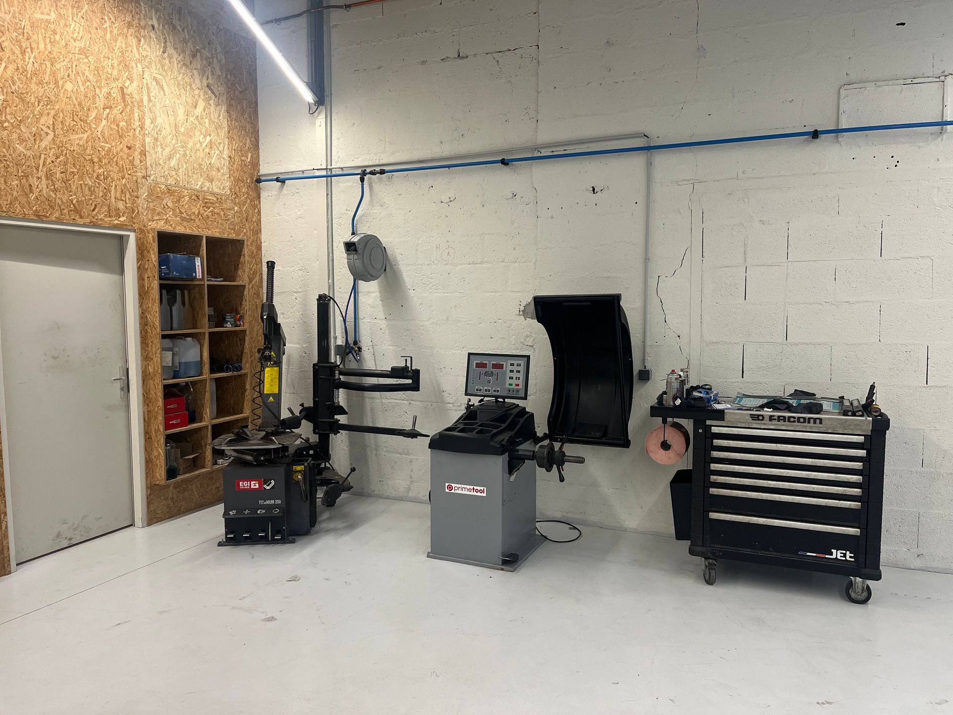 Un atelier de garage comprenant un démonte-pneus, une équilibreuse de roues, une caisse à outils.