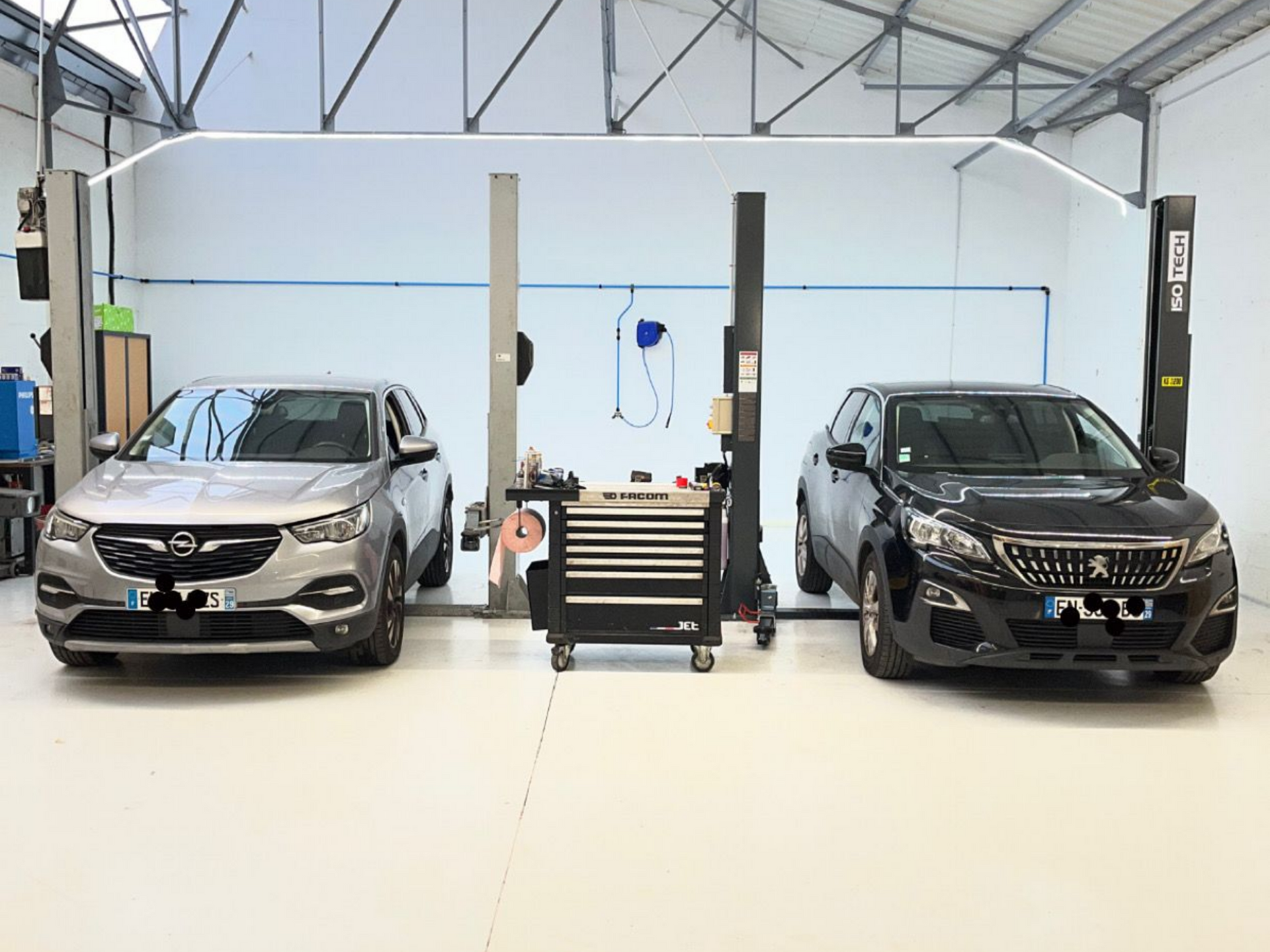 Deux voitures garées dans un atelier de réparation automobile.