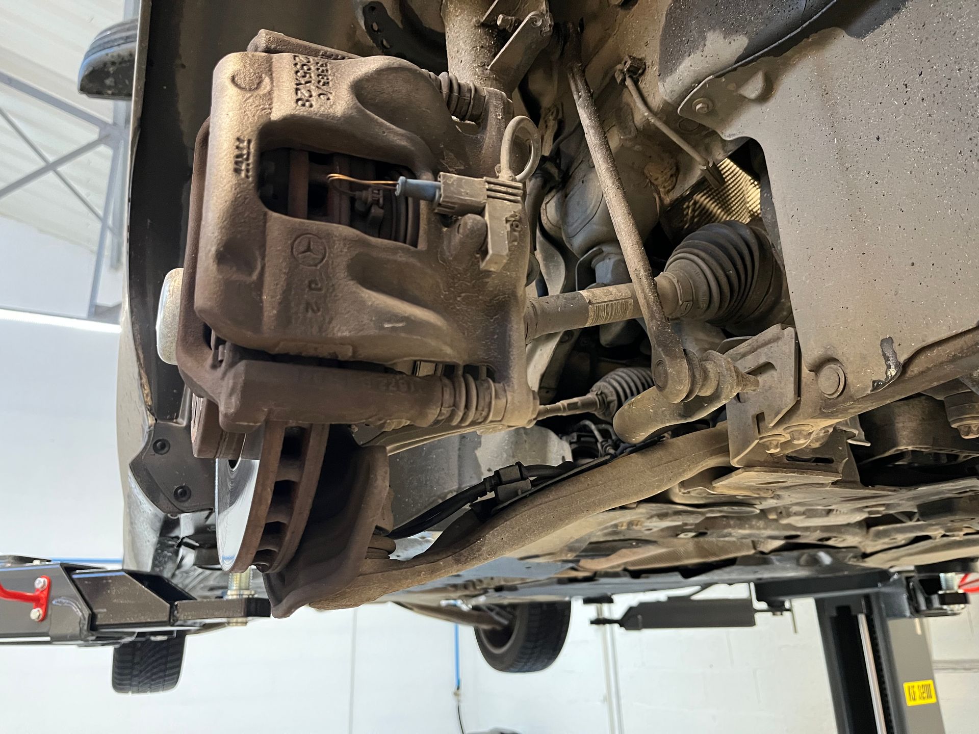 Gros plan sur la suspension avant, le disque de frein et l'étrier de frein d'un véhicule.