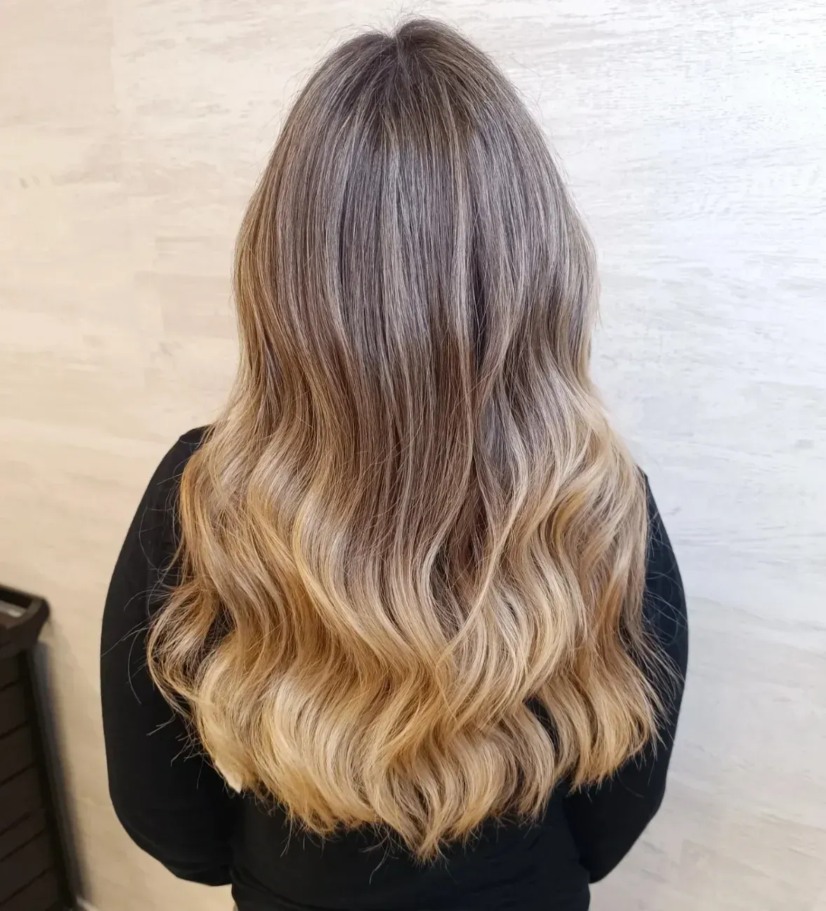 Una persona vista de espaldas, mostrando una larga melena ondulada con una transición de color degradada de castaño a rubio.