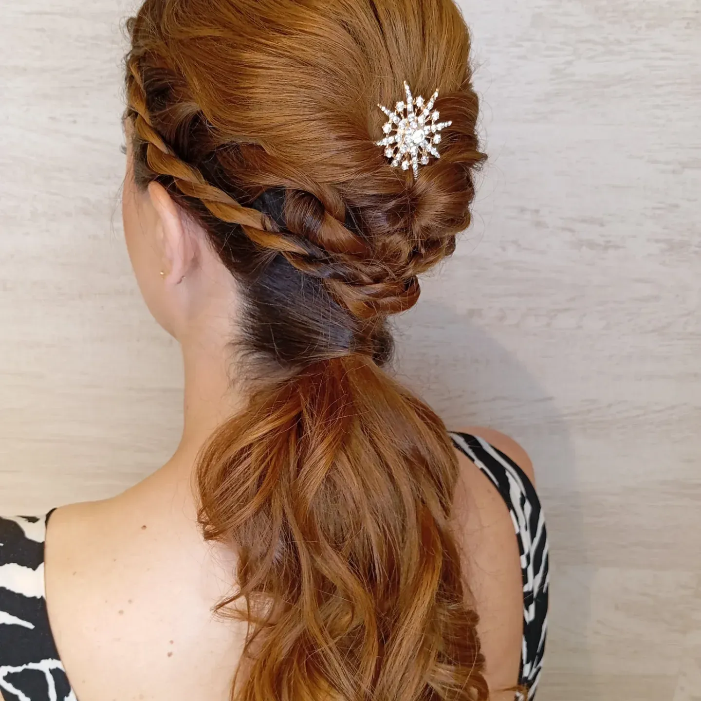 Una persona con cabello castaño rojizo peinado en un semirecogido con un moño, adornado con un accesorio para el cabello plateado brillante en forma de estrella.