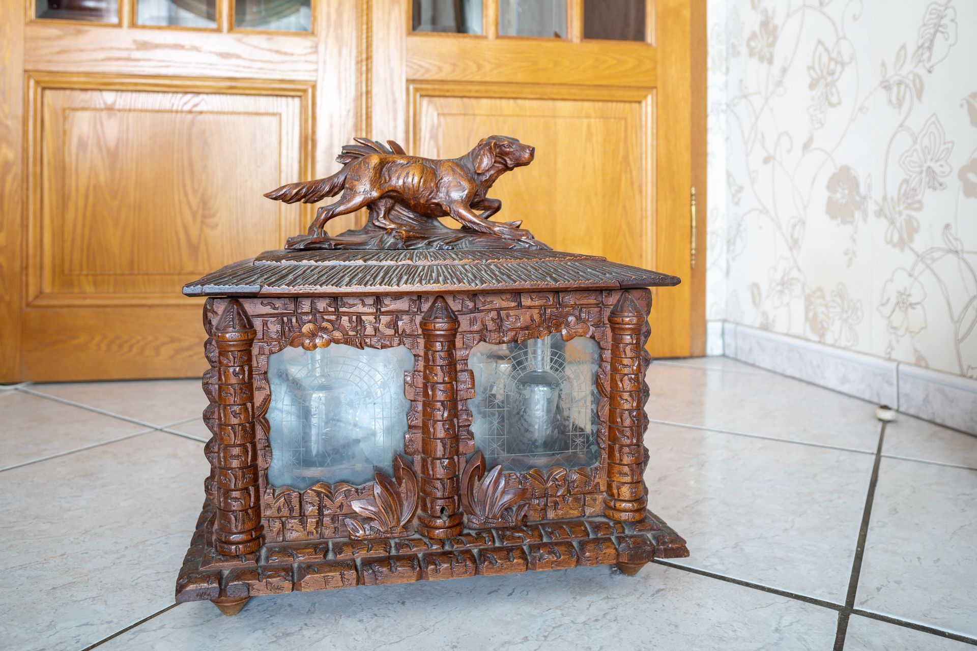 Armoire en bois ornée de détails sculptés et surmontée d'une figurine de chien