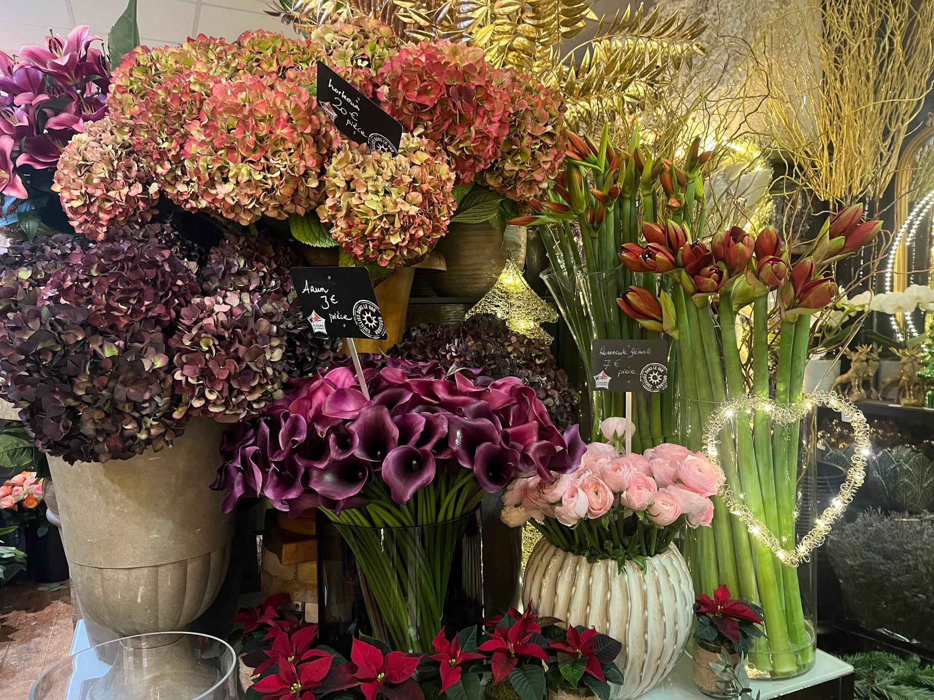 Bouquets et compositions florales colorées assorties dans une vitrine de fleuriste.