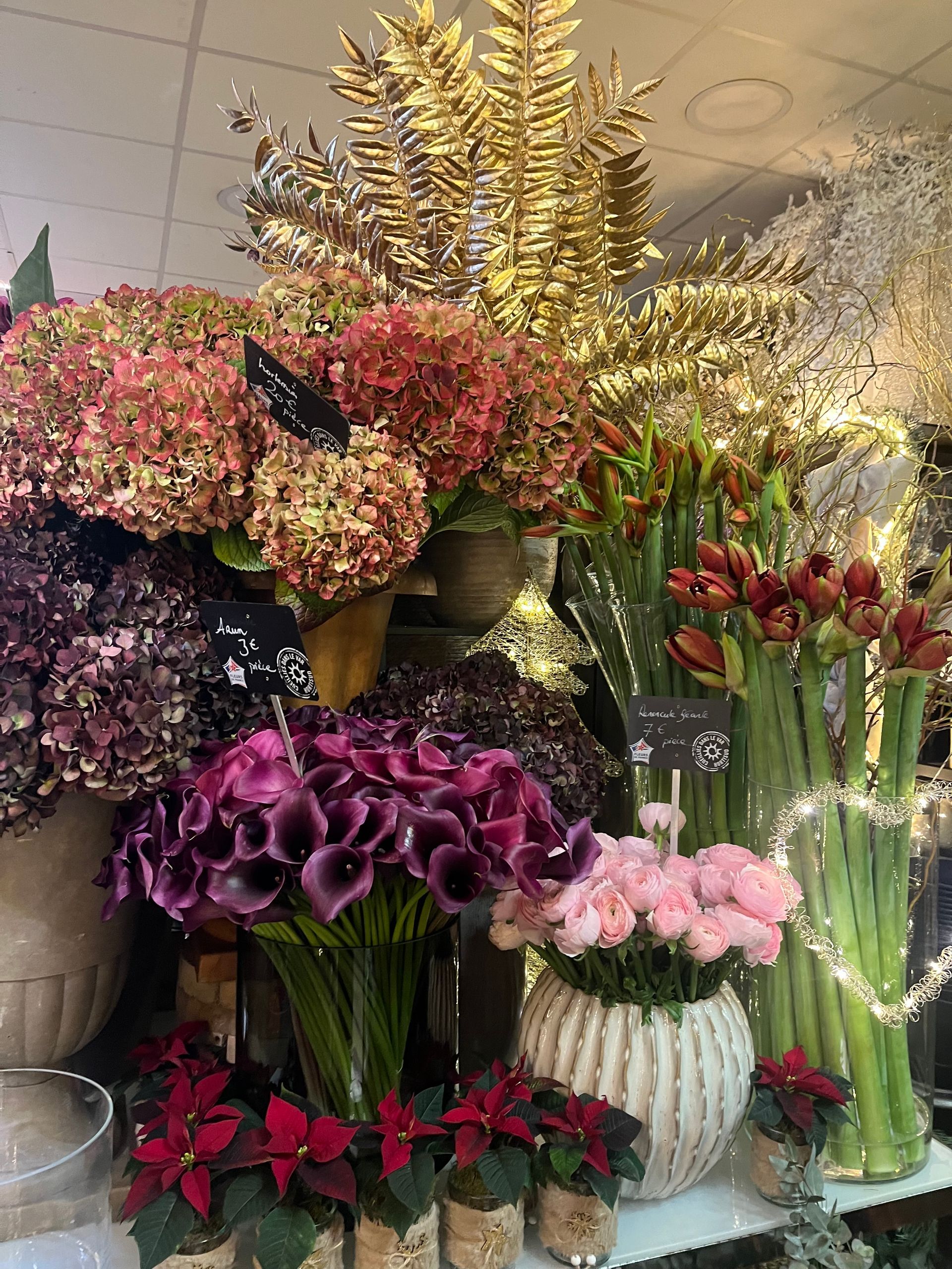 Présentation de bouquets colorés avec des fleurs roses, violettes, rouges et jaunes dans des vases.