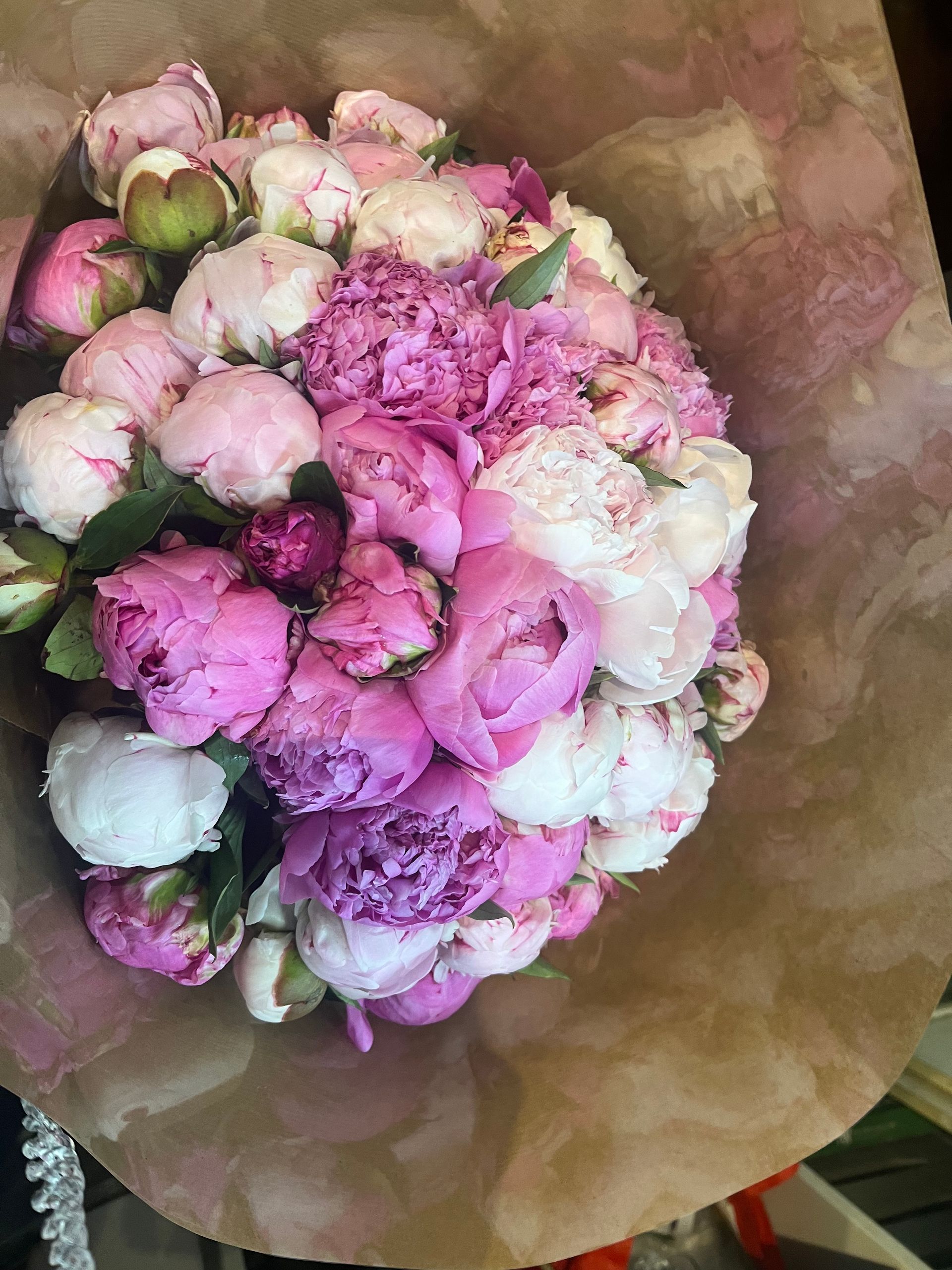 Bouquet de fleurs roses et blanches enveloppé dans du papier brun.
