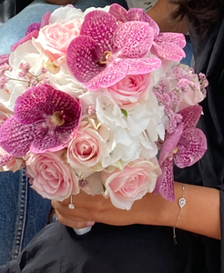 Bouquet de fleurs roses et blanches tenu dans les bras d'une personne.