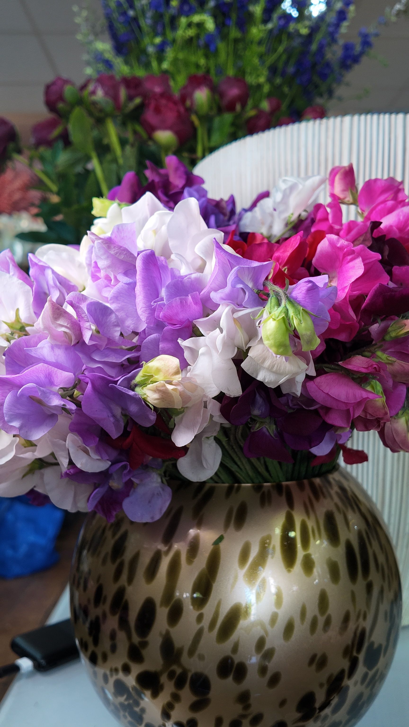 Des fleurs violettes et blanches dans un vase à pois sur une table.