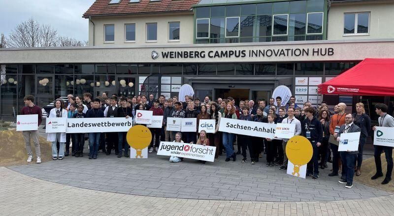 Eine große Gruppe von Menschen steht mit Schildern vor einem Gebäude.