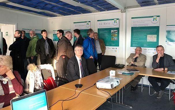 Eine Gruppe von Leuten sitzt in einem Raum um einen Tisch herum.