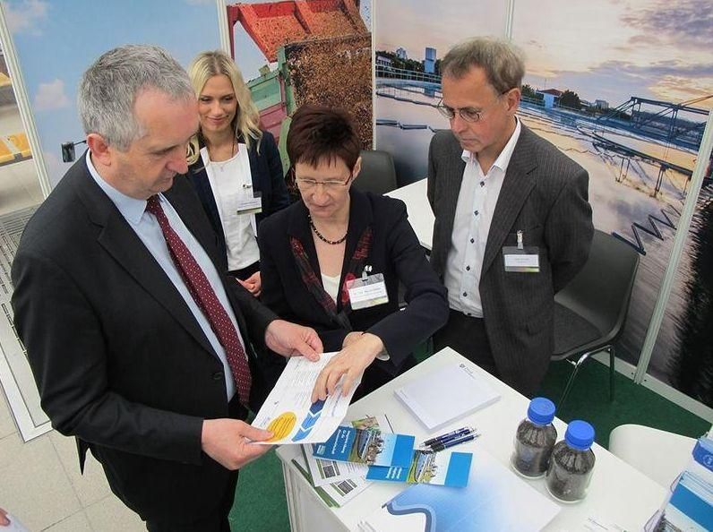 Eine Gruppe von Menschen steht um einen Tisch herum und schaut sich etwas an