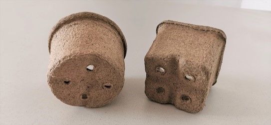 Zwei kleine Töpfe aus Kork stehen nebeneinander auf einem Tisch.