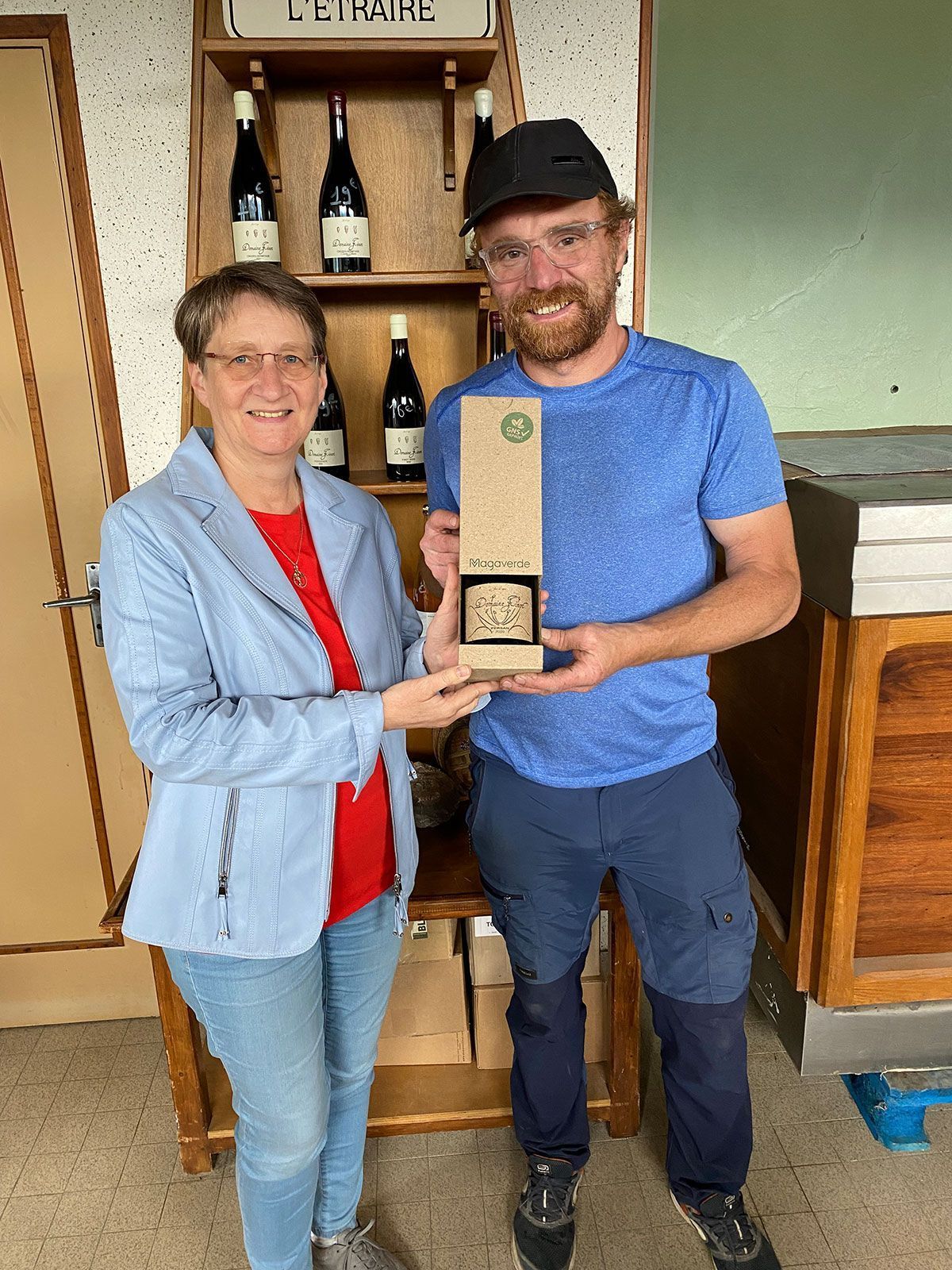 Ein Mann und eine Frau stehen nebeneinander und halten eine Flasche Wein in der Hand.