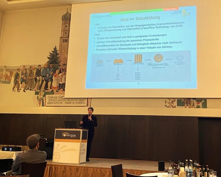 Ein Mann hält in einem Konferenzraum vor einem großen Bildschirm eine Präsentation.