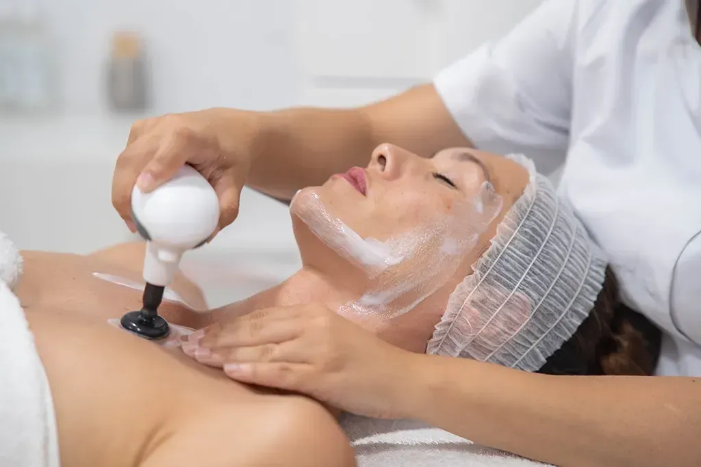 Tratamiento facial en un spa, con la aplicación de una crema mientras el cliente está tumbado en una camilla de masaje