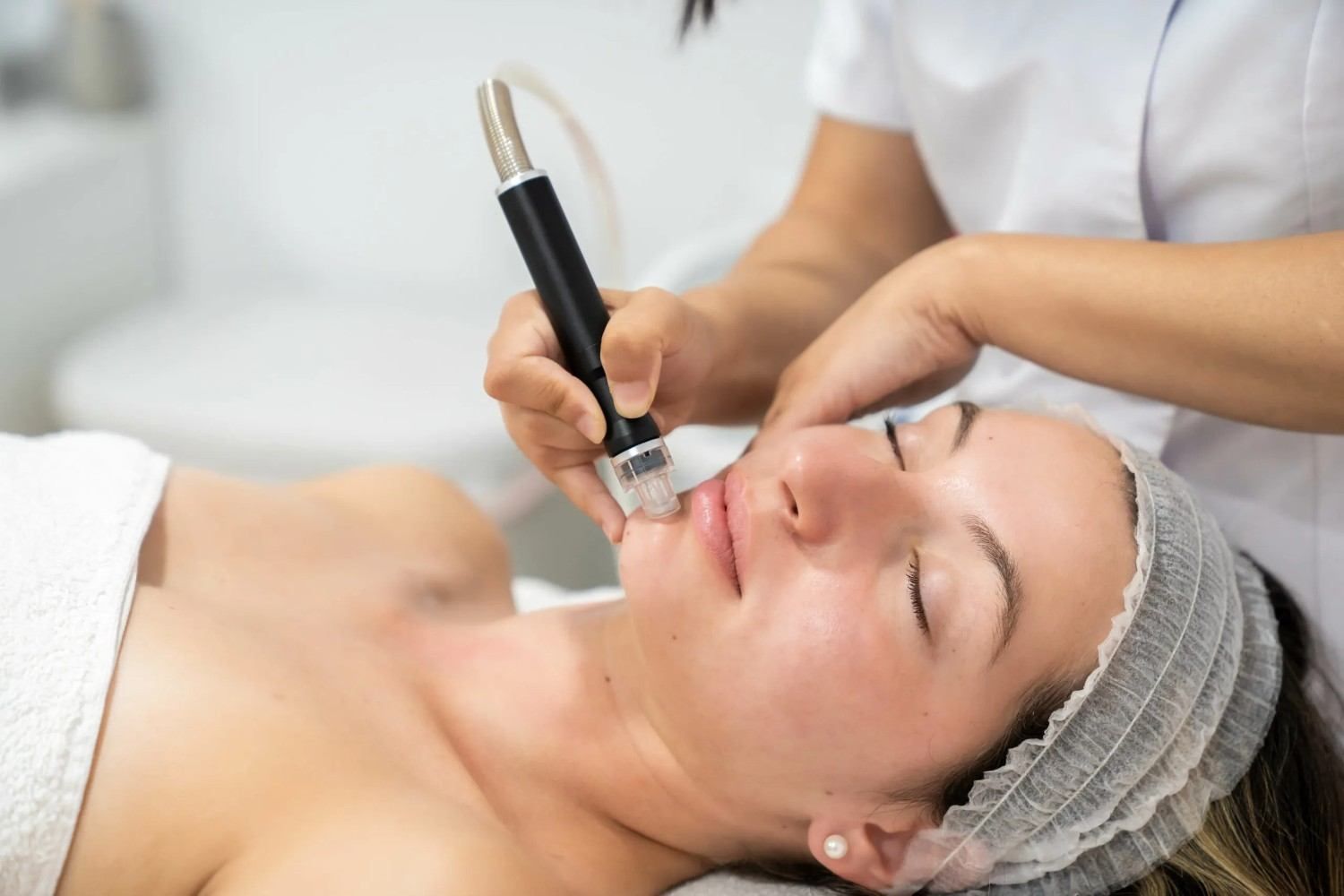 Tratamiento facial cosmético con un dispositivo portátil a una mujer tumbada