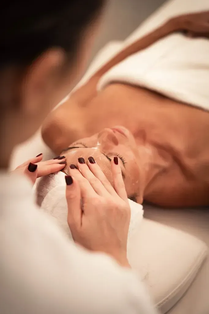 Manos sosteniendo una toalla blanca sobre el abdomen desnudo de una persona durante un masaje o tratamiento de spa