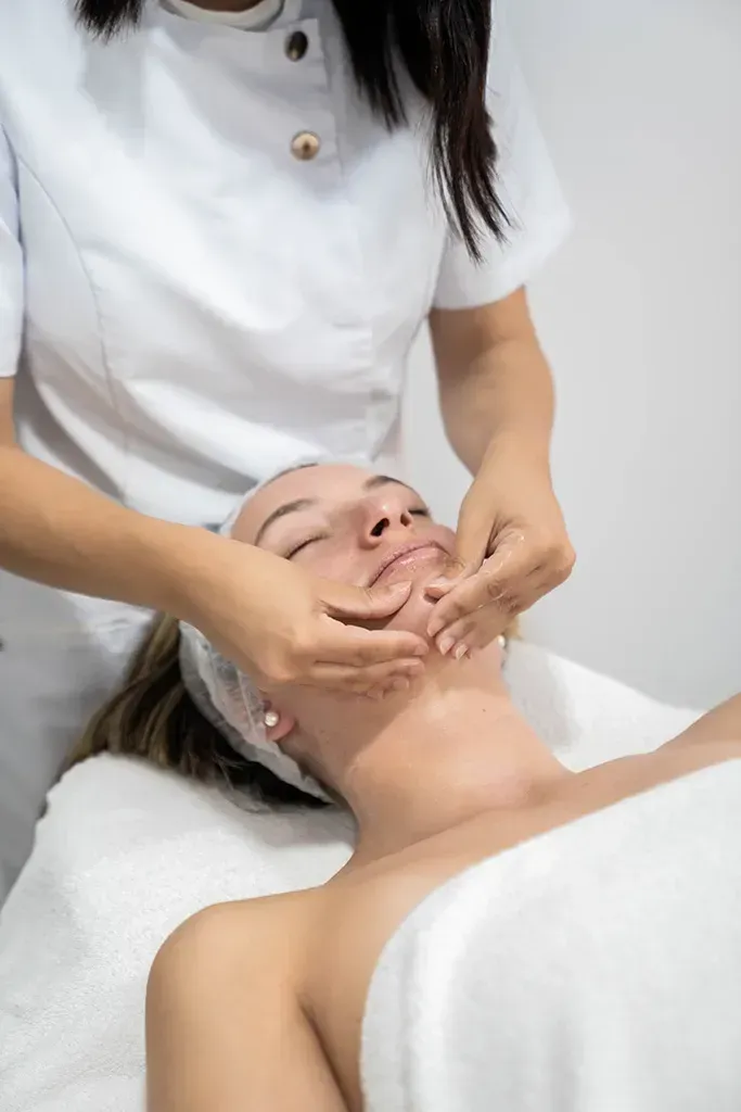 Masaje facial en una sala de spa, con un cliente tumbado bajo una toalla.